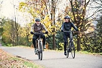 Ein älterer Mann und eine Frau fahren in einem Park Fahrrad.