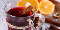 Ein Glas Glühwein mit Zimtstange und Orangenscheiben