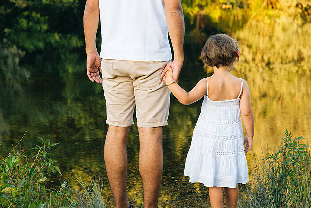 Erfahrungsbericht: Leben mit einem fetalen Alkoholsyndrom Vater hält ein kleines Mädchen an der Hand