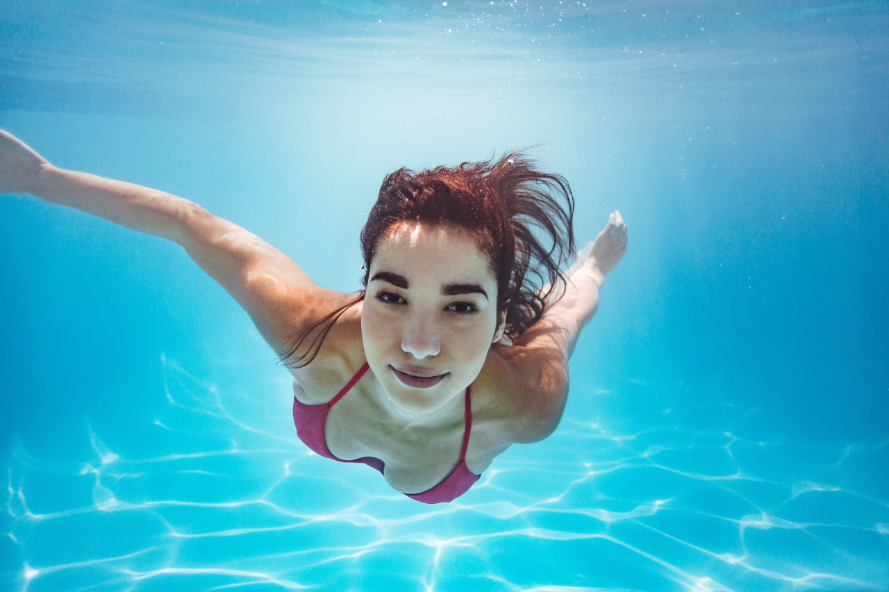 Mädchen schwimmt unter Wasser. Foto: Adobe Stock.