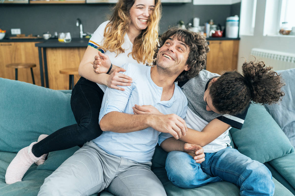 Ein Vater tollt mit seinen Kindern auf dem Sofa herum